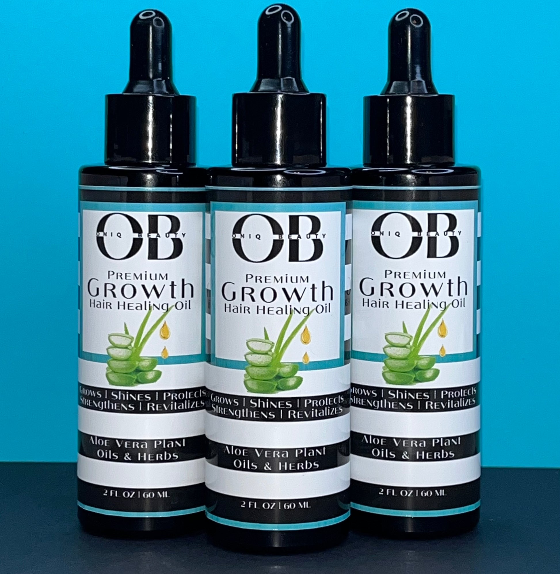 Three black 2ml, 60 fl oz glass bottles of herbal hair growth oil. ONIQ Beauty Premium Growth Hair Healing Oil with Aloe Vera, Oils and Herbs. Vegan, Alcohol-free, Chemical-Free, Not tested on animals. The oil has Aloe Vera, oils and herbs.